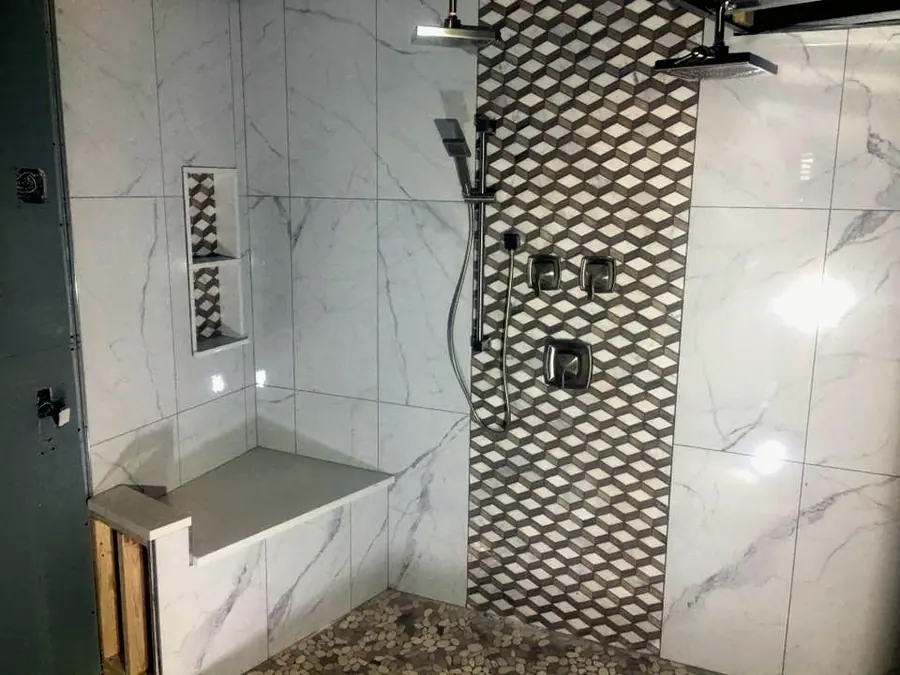Tiled walk-in shower with a bench, niche and patterned accent wall